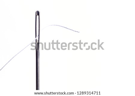 Needle and thread on a white background. Macro of a needle's eye and thread.