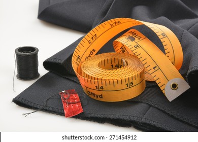 Needle and tread with a measuring tape on pants that need a hem put in