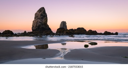 The Needles sea stacks alongside the beach at Cannon Beach Oregon during low tide at dawn