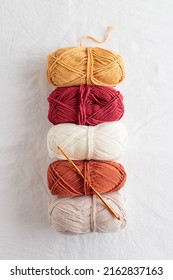 Needlework. Balls Of Cotton Yarn Warm Colors With A Hook On A White Table, Copy Space