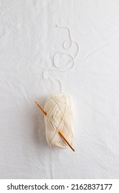 Needlework. Crochet Hook And Ball Of Cotton Yarn White Color On A White Table, Copy Space