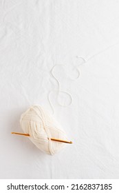 Needlework. Crochet Hook And Ball Of Cotton Yarn White Color On A White Table, Copy Space