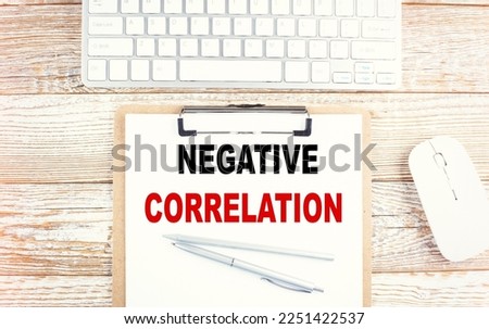 NEGATIVE CORRELATION text on a clipboard with keyboard on a wooden background