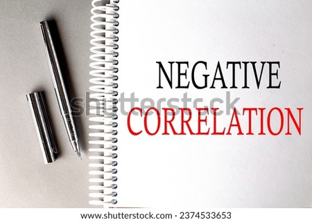 NEGATIVE CORRELATION text on notebook with pen on grey background