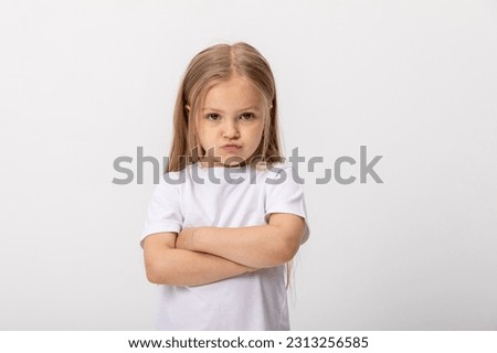 Negative human emotions, reactions and feelings. Isolated shot of moody displeased angry little girl crossing arms on her chest, pouting lips, having offended facial expression, being capricious