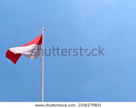 negative space of red and white flag of Indonesia flutters on a pole against a bright blue sky as a background