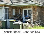 NEGLECTED TRASHED SUBURBAN HOME - Need a handyman, cleaner or gardener?  Rubbish, hoarding and clutter removal. An overgrown old brick house entrance with weeds, bicycle and abandoned junk and bins