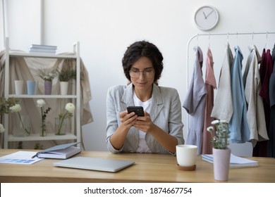 Negotiations online. Interested young woman florist designer using cellphone at workplace in home office studio. Tailor dressmaker calling contacting client customer supplier to discuss order details