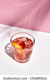 Negroni Cocktail Over Pink Background. Drink In Rox Glass In Daylight With Palm Leaf Hard Shadow. Summer, Tropical, Fresh Drink Concept.