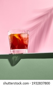 Negroni Cocktail Over Pink Background. Drink In Rox Glass In Daylight With Palm Leaf Hard Shadow. Summer, Tropical, Fresh Drink Concept.