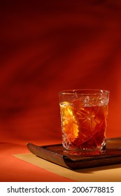 Negroni Cocktail Served Above Wooden Plate On Orange Background With Shadow Of Palm Leaves 