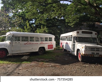 Negros Oriental, Philippines; November 18, 2017: Two vintage school buses of Silliman University are parked askew under the shade of large trees.