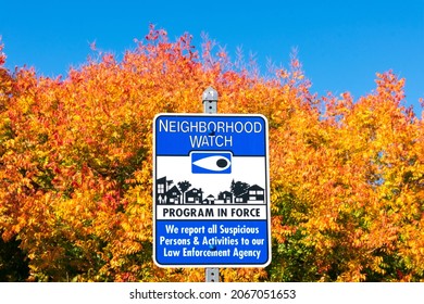 Neighborhood Watch Program In Force Sign. Amazing Bright Red, Yellow Fall Colored Trees Background