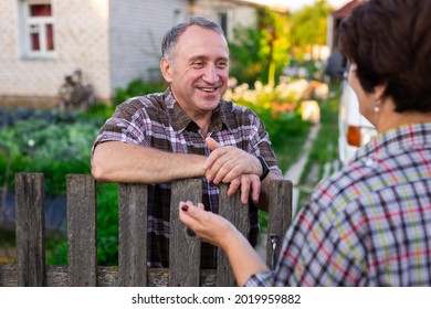 neighbors middle aged man and woman chatting near the fence in the village