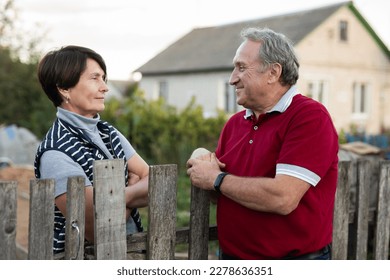 Neighbors standing at fence outdoors and having - Shutterstock ID 2278636351