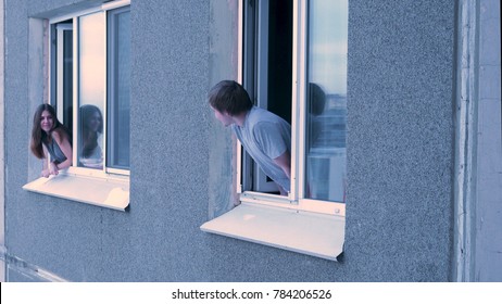 Neighbors talk to each other from the window. Young happy couple conversing in window. Neighbors concept. Young couple having a conversation while looking at each other over a window background