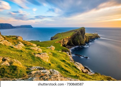 Neist Point Lighthouse on the Isle of Skye bathed in golden light from the setting sun.