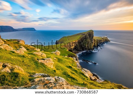 Neist Point Lighthouse on the Isle of Skye bathed in golden light from the setting sun.