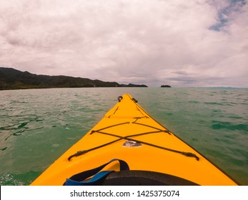 Nelson, New Zealand - Jan 2019: Perspective View From Yellow Kayak, Looking Out To Sea. View Of Mountains, Ocean, Yellow Kayak, Paddle And Rocks. Turquoise Sea. Abel Tasman National Park