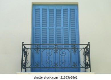 Neoclassical house balcony railing and wooden window shutter.