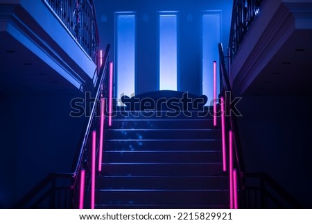 Neon Background. Dark blue and red neon stairs at the night. Night club, bar, concert or studio room. Fluorescent laser light. 