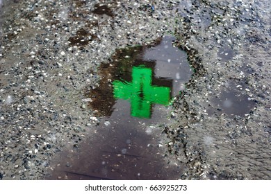 Neon cross, pharmacy sign, with burning lights in the form of a heart reflected in a puddle on the asphalt in rainy weather. For wallpaper, advertising, design, covers, background, textures. - Powered by Shutterstock