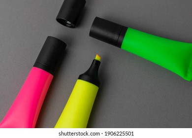 neon highlighter pens on a grey background