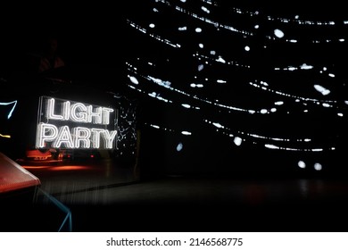 Neon inscription LIGHT PARTY on the wall. Multicolored neon inscription LIGHT PARTY on dark background