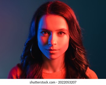 Neon Light People. Retro Wave Portrait. Split Personality. Hot And Cold. Pretty Smiling Young Woman Face In Bright Colorful Red Blue Glow Isolated On Dark Background.