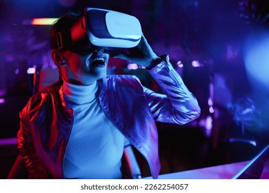 Neon metaverse futuristic concept. smiling trendy female in vr headset testing out virtual reality in modern office. - Powered by Shutterstock