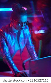 Neon metaverse futuristic concept. trendy woman in glasses with laptop in modern office. - Shutterstock ID 2310527115