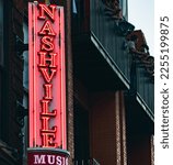 Neon music sign in downtown Nashville, Tennessee with people cheering on bar balcony