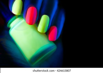 Neon Nails. Fashion model woman nails in neon light, beautiful nail art with fluorescent nail polish, Art design of female colorful disco nailart in UV, Isolated on black background