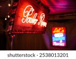 A neon "Parlor Room" sign in bright red script on a wooden background with zebra-patterned edges, creating a cozy, retro ambiance. Blurred background neon lights add playful contrast