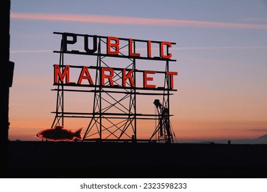 A neon public market sign at Pike Place Market and Elliott bay during the sunset - Powered by Shutterstock