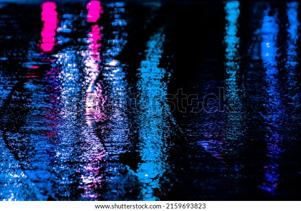 Neon reflection
from street asphalt with pedestrian walking by. Futuristic city and
cyberpunk concept.