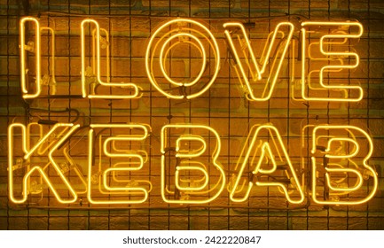 Neon shining sign in yellow warm color on a brick wall with the inscription or slogan I love kebab. Brick wall, background. Bright electric neon light. Cafe-restaurant Doner Kebab