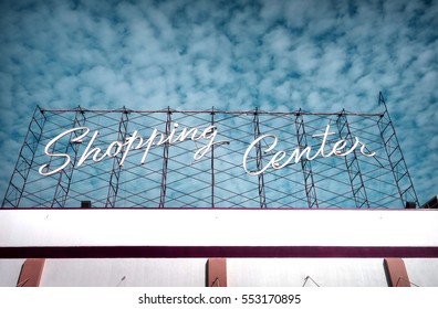 Neon Shopping Center Sign And Cloudy Sky                              