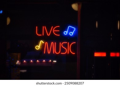 A neon sign advertising live music is lit up in primary colors in the window of an eating establishment. - Powered by Shutterstock