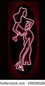 Neon Sign Full Size Naked Woman In Heels Showing Entrance To Night Strip Dance Club Bar In Red District Of Urban City Adult Entertainment.