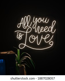Neon sign inscription all you need is love on a dark background. Love concept