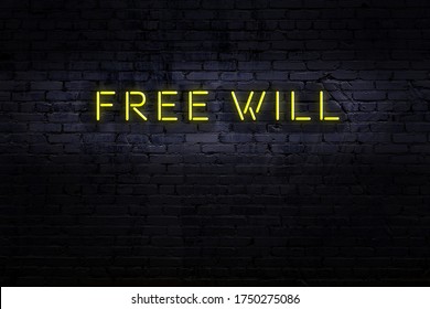 Neon Sign With Inscription Free Will Against Brick Wall. Night View