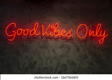 Neon with the word good vibes only, on wall texture.