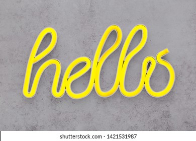 Neon Yellow Hello Sign On A Grey Concrete Background