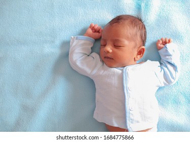 a neonatal infant baby sleeping in peace on a sky colored towel with copy space for text
