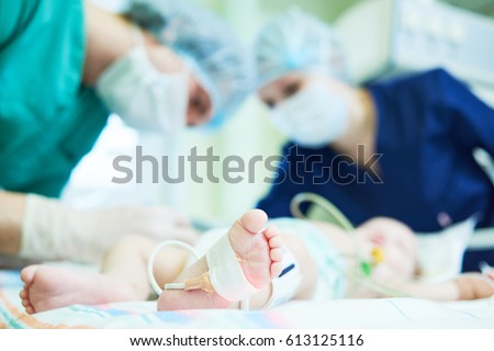 Neonatal Resuscitation. Doctor's team doing intensive therapy to newborn baby