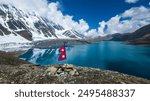 Nepal national flag fluttering in the wind on the shores of Tilicho Lake, the highest Lake of Nepal and 5000 meters