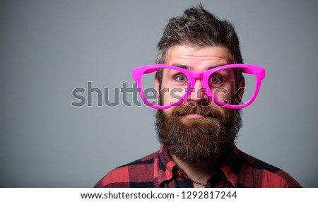 Nerd concept. Hipster looking through of giant pink eyeglasses. Man beard and mustache face wear funny big eyeglasses. Life in pink color. Naivety man. Naivety and simplicity. Adult but still naivety.