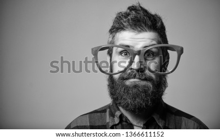 Nerd concept. Hipster looking through of giant pink eyeglasses. Man beard and mustache face wear funny big eyeglasses. Life in pink color. Naivety man. Naivety and simplicity. Adult but still naivety.