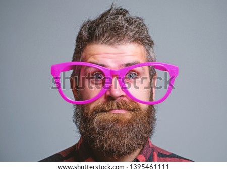 Nerd concept. Hipster looking through of giant pink eyeglasses. Man beard and mustache face wear funny big eyeglasses. Life in pink color. Naivety man. Naivety and simplicity. Adult but still naivety.